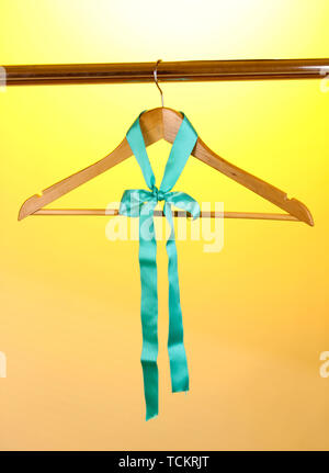 Bellissimo il turchese bow appeso su appendiabiti in legno su sfondo giallo Foto Stock