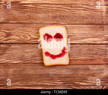 Fetta di pane con un sorriso su un di legno Foto Stock