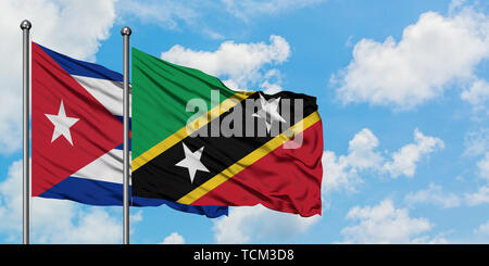 Cuba e Saint Kitts e Nevis bandiera sventolare nel vento contro bianco torbido cielo blu insieme. Concetto di Diplomazia e relazioni internazionali. Foto Stock