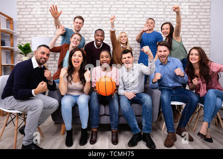 Il gruppo di allegro amici guardare la partita di basket insieme a casa Foto Stock