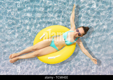 Angolo di Alta Vista di una donna galleggiante sul galleggiante giallo in acque poco profonde a Beach Foto Stock