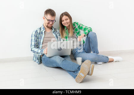 Affascinante giovane donna e un uomo sorridente sta guardando i negozi online utilizzando un computer portatile per acquistare impianti idraulici in un nuovo appartamento. Inaugurazione della casa nuova e il concetto di riparazione. Foto Stock