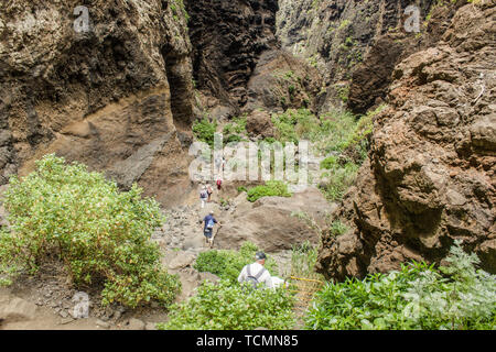 Rocce nel Masca gorge, Tenerife, mostrando solidificato di lava vulcanica di strati di flusso e la formazione di arco. Il burrone o barranco conduce all'oceano fr Foto Stock