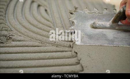 Lavoratore installazione di muro di pietra superficie con cemento per la casa di rinnovamento. Lavoratore con una spatola e piastrelle Foto Stock