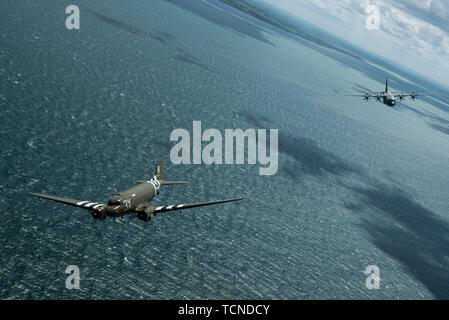 Un Douglas C-47 Dakota, soprannominato "che è tutto il fratello", vola con U.S. Air Force C-130J Super Hercules, assegnato per la trentasettesima Airlift Squadron, Ramstein Air Base, Germania, oltre la Manica, Giugno 8, 2019. La trentasettesima Troop Carrier Squadron, il squadrone legacy per la trentasettesima come, indossava il "W7" o "Whiskey 7 segni durante il funzionamento Nettuno, Giugno 6, 1944. "Che è tutto il fratello" ha volato operazioni durante l invasione della Normandia. (U.S. Air Force foto di Senior Airman Devin M. Rumbaugh) Foto Stock