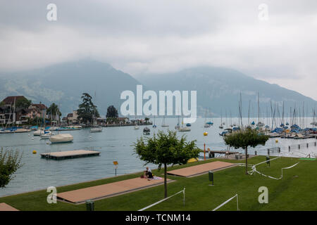 Vista sulla città di Spiez e del lago di Thun, Svizzera, Europa. Estate giornata del sole, drammatica azzurro cielo nuvoloso e lontane montagne Foto Stock