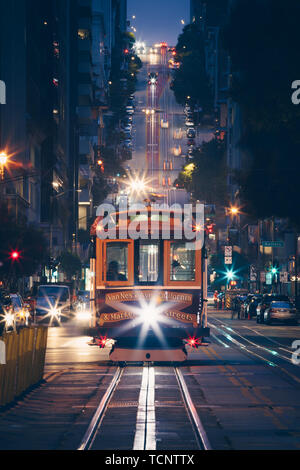 Visualizzazione classica della storica tradizionale cavo auto equitazione sulla famosa California Street durante la notte con le luci della città di San Francisco, California, Stati Uniti d'America Foto Stock