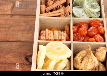 Frutta secca e cannella nella casella su sfondo di legno Foto Stock