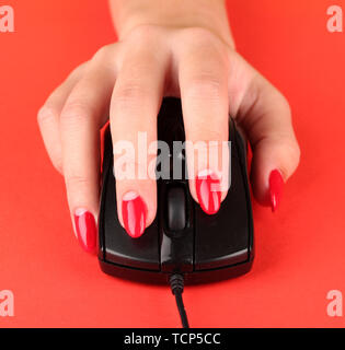 Primo piano della femmina di dita e le unghie sul mouse del computer sul colore di sfondo Foto Stock