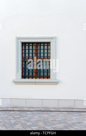 Background urbano. Muro Bianco con finestre piccole e griglia di ferro Foto Stock