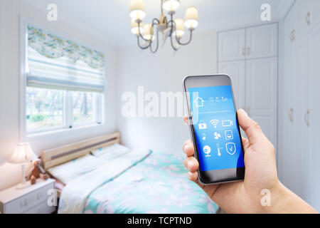Telefono cellulare con smart home app in una moderna camera da letto Foto Stock