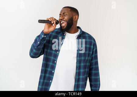 Ritratto di Allegro chic positivo bello uomo africano tenendo il microfono a cantare il canto. Isolato su sfondo bianco. Foto Stock