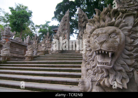 Immagine di un leone statua di pietra con una tipica Balinese ingresso gate in backround. Questa è situato presso la pura Dalem tempio in Ubud, Bali, Indones Foto Stock