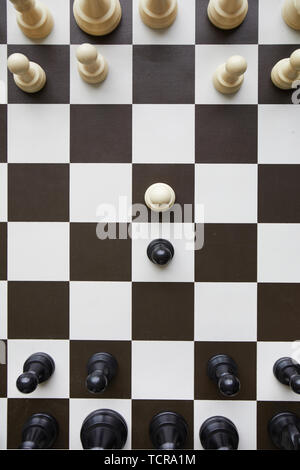 Vista da sopra il bianco e nero a scacchi in legno pezzi permanente sulla partita a scacchi board Foto Stock
