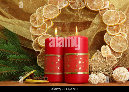 Due candele e decorazioni di Natale, su sfondo dorato Foto Stock