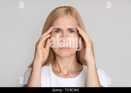 Sottolineato donna matura toccando i templi, avendo mal di testa Foto Stock