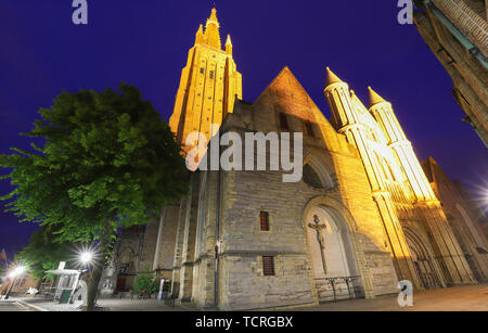 Vista notturna di una tipica strada del centro storico di Bruges, con la Chiesa di Nostra Signora come sfondo, Belgio Foto Stock