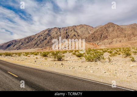 La strada attraverso un deserto e montagne in California, Stati Uniti d'America Foto Stock