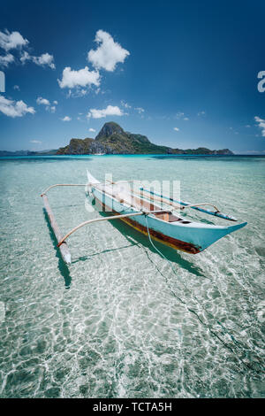 Piccola pesca barca banca di fronte Cadlao Island in cristalline acque poco profonde, bassa marea, natura straordinaria di Palawan, Filippine Foto Stock