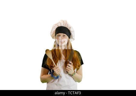 Redhead teen chef con il coltello e il cucchiaio di legno in chef hat e grembiule isolato su bianco con copyspace. Foto Stock