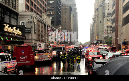 New York, Stati Uniti d'America. Decimo Giugno, 2019. I vigili del fuoco, la polizia e i servizi di salvataggio sono in servizio vicino la scena dell'incidente. Almeno una persona è morto in un incidente in elicottero su un grattacielo a New York del distretto di Manhattan. Il crash si è verificato sulla Settima Avenue nel cuore di Manhattan vicino alla famosa Times Square. Credito: Benno Schwinghammer/dpa/Alamy Live News Foto Stock