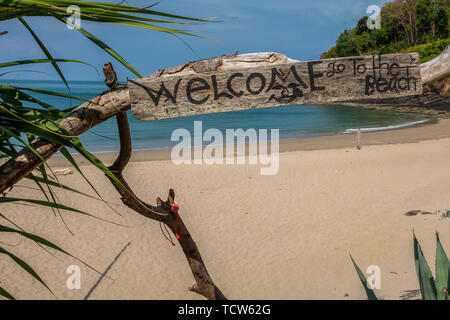 Una vista di una spiaggia con un rustico di segno positivo sull'isola di Koh Lanta, Thailandia, la spiaggia è totalmente vuota e idilliaco con la frizzante Andaman Foto Stock