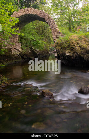 Una vista dell'antico ponte di Cromwell in Kenmare, nella contea di Kerry, Irlanda, preso da monte su una lunga esposizione per lisciare fuori l'acqua, nessuno in Foto Stock