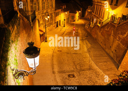 Vista dal ponte di bugiardi (Podul Minciunilor) a Sibiu, in Romania, di notte, con belle, artistico in stile medievale lampada di strada e scale. Popolare turi Foto Stock