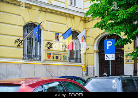 Sibiu, Romania, 27 Maggio 2019: Sibiu County Council (Consiliul Judetean Sibiu) edificio - Vista esterna durante il giorno, con le bandiere della Romania, Europee UNI Foto Stock