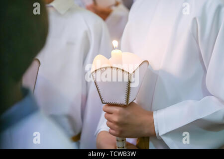 I bambini sulla prima santa Comunione nella Chiesa. Dettaglio dei figli tenendo premuto il Santo illuminato candela durante l omelia della Santa Messa di Prima Comunione. Foto Stock