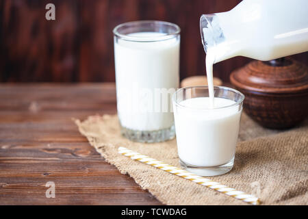 Versando in casa il kefir, yogurt con probiotici probiotico di freddo latticini fermentati bevanda alla moda di cibi e bevande spazio copia stile rustico Foto Stock