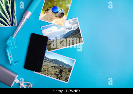 Smartphone con schermo vuoto e volantini e foto su uno sfondo blu. Mock up, piatto laici. La vacanza estiva concetto. Foto Stock