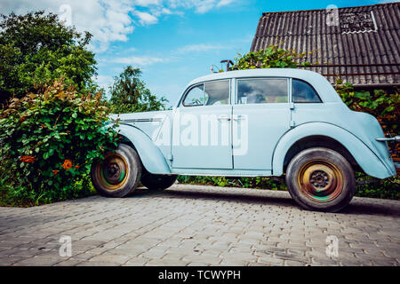 Molto vecchia auto su uno sfondo di fiori Foto Stock