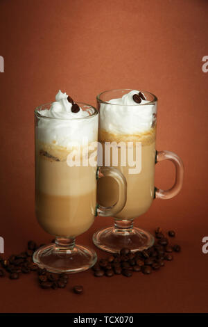 Fragranti caffè latte in bicchieri Tazze, su sfondo marrone Foto Stock