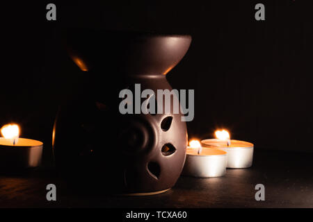 Tradizionale diffusore di aroma con candele in retro, immagine scura con contrasto elevato Foto Stock