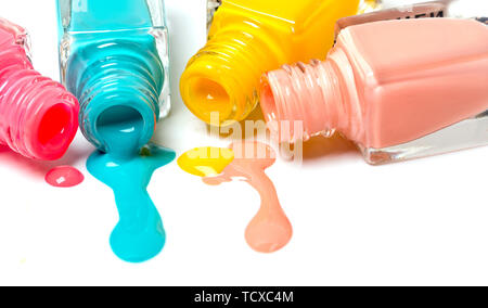Bottiglia di smalto per unghie in diversi colori su sfondo bianco, versando il smalto per unghie Foto Stock