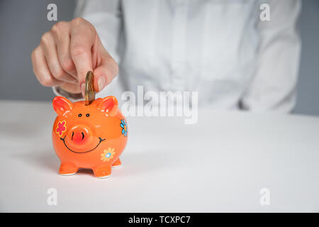 Risparmio di denaro, assicurazione di rendita, il pensionamento e il concetto di persone - close up di senior donna mettendo mano moneta nel salvadanaio Foto Stock
