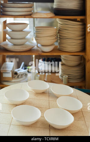 Immagine di sfondo di ciotole di porcellana sul tavolo in studio artigianale, spazio di copia Foto Stock