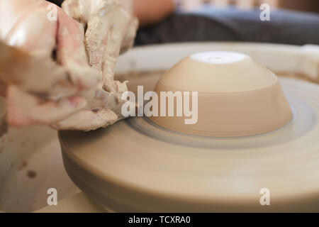 Extreme closeup di irriconoscibile potter femmina di argilla di sagomatura sulla ruota durante il lavoro in studio, spazio di copia Foto Stock