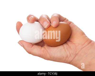 Mano con due differenti uova di colore. Marrone e bianco. Isolato su bianco. Foto Stock