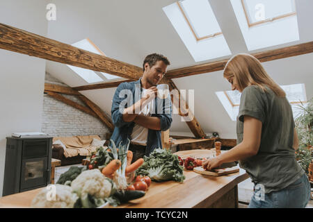 Moda giovane sbucciare e tagliare le verdure dal mercato in cucina rustica Foto Stock