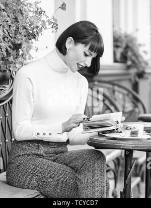 Ragazza bere il caffè leggere il libro. La tazza di un buon caffè e libro piacevole combinazione migliore per un perfetto fine settimana. La donna bere godono di un buon libro cafe terrazza. Miglioramento di auto concetto. La letteratura per femmina. Foto Stock