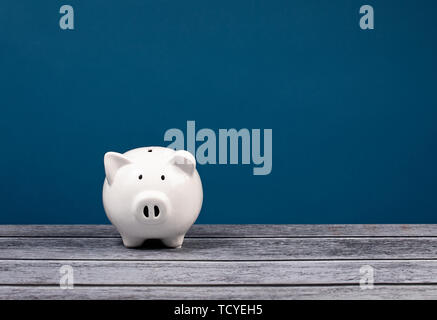 Carino white Salvadanaio su un blu e grigio. Foto Stock