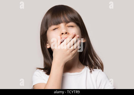 Bambina sbadigli ritiene sleepy isolato sul beige di sfondo per studio Foto Stock