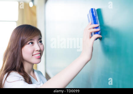 Bella ragazza giovane con lavagna verde in aula Foto Stock