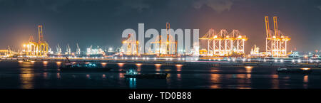 Vista panoramica di gru di carico contenitori di spedizione in spedizione cargo porto di notte, banner dimensioni. Importare o esportare business, industria logistica Foto Stock