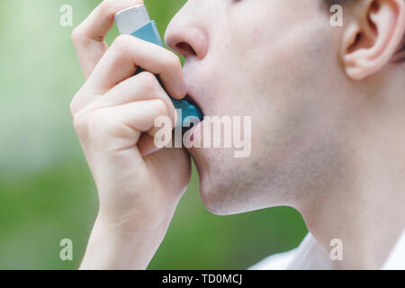 Giovane uomo è utilizzando un inalatore per asmatici Foto Stock