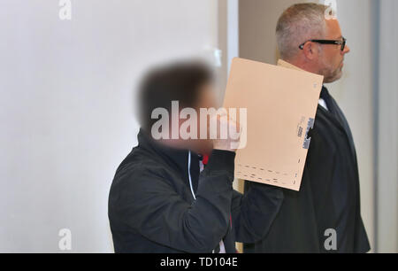 Memmingen, Germania. 11 Giugno, 2019. Un 43-anno-vecchio (m) rappresenta con il suo avvocato Thorsten Storp (r) in un aula di tribunale distrettuale e contiene un file il coperchio davanti al suo volto. L'uomo è caricato con il tentato omicidio con una balestra. Credito: Karl-Josef Hildenbrand/dpa/Alamy Live News Foto Stock