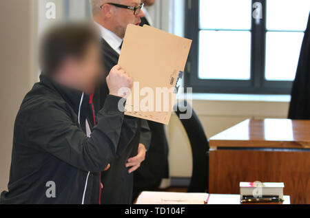 Memmingen, Germania. 11 Giugno, 2019. Un 43-anno-vecchio (m) rappresenta con il suo avvocato Thorsten Storp (r) in un aula di tribunale distrettuale e contiene un file il coperchio davanti al suo volto. L'uomo è caricato con il tentato omicidio con una balestra. Credito: Karl-Josef Hildenbrand/dpa/Alamy Live News Foto Stock