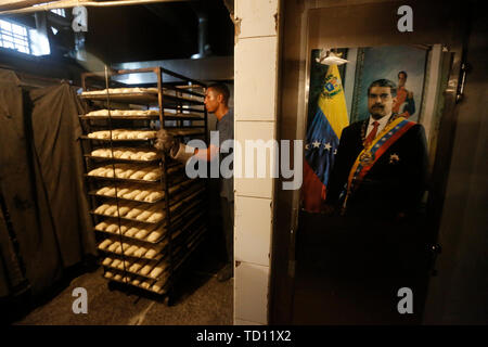 05 giugno 2019, Venezuela, Caracas: un poster raffigurante il presidente Nicolas Maduro accanto a una bandiera venezuelana si blocca in prossimità del forno in 'La Minka', un panificio gestito da sostenitori del governo. L'ex panificio privato è stato chiamato 'Mansion's Bakery'. Ora circa 6.000 pezzi di pane sono prodotte ogni giorno a prezzi fissati dallo stato. Il paese con la più grande riserva di petrolio nel mondo è in un drammatico declino. La svalutazione del denaro è il più alto del mondo, per molte persone il cibo è insostenibile. Questi "' Bolivariana panetterie, che vendono il pane a prezzi fissi e vedere la loro attività come parte del "socialismo di t Foto Stock